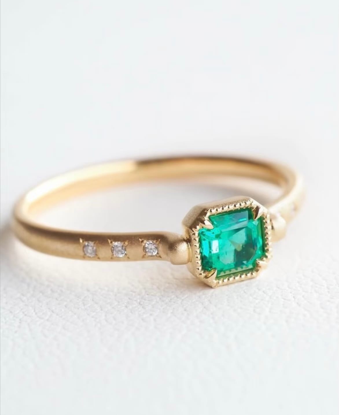 Emerald ring on a matte gold band with star-set diamonds